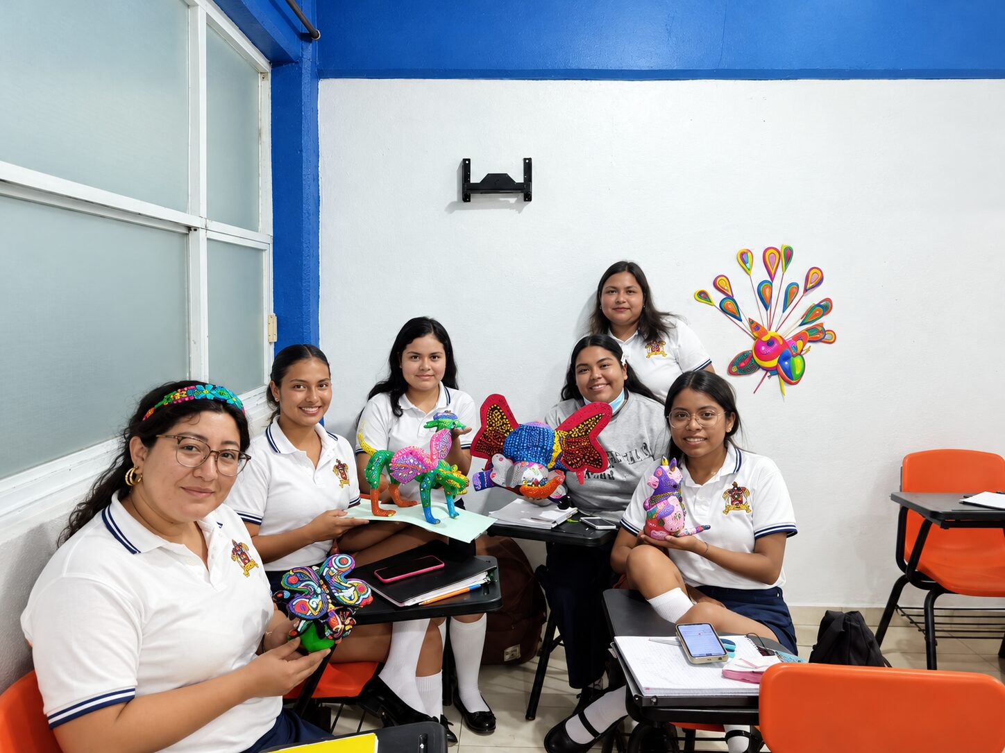 Estudiantes de Pedagogía de CEUSJIC sonrientes con sus alebrijes en el aula
